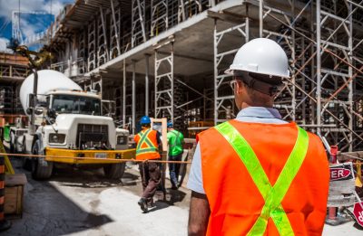 Construction worker onsite looking at a large truck.