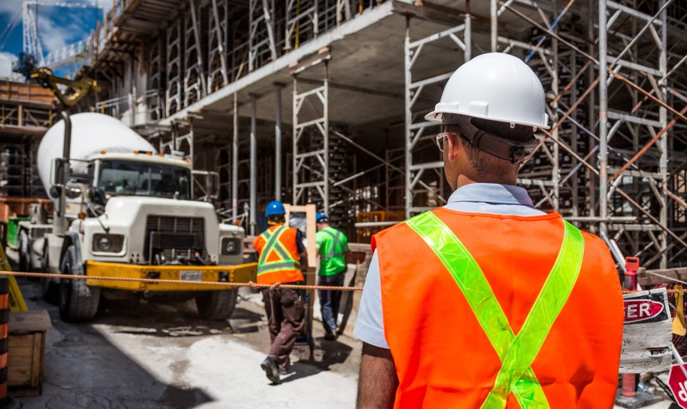 Construction worker onsite looking at a large truck.